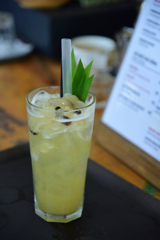 pexels photo 32887162 Iced pineapple drink with tropical leaf garnish served in a tall glass on a wooden table.