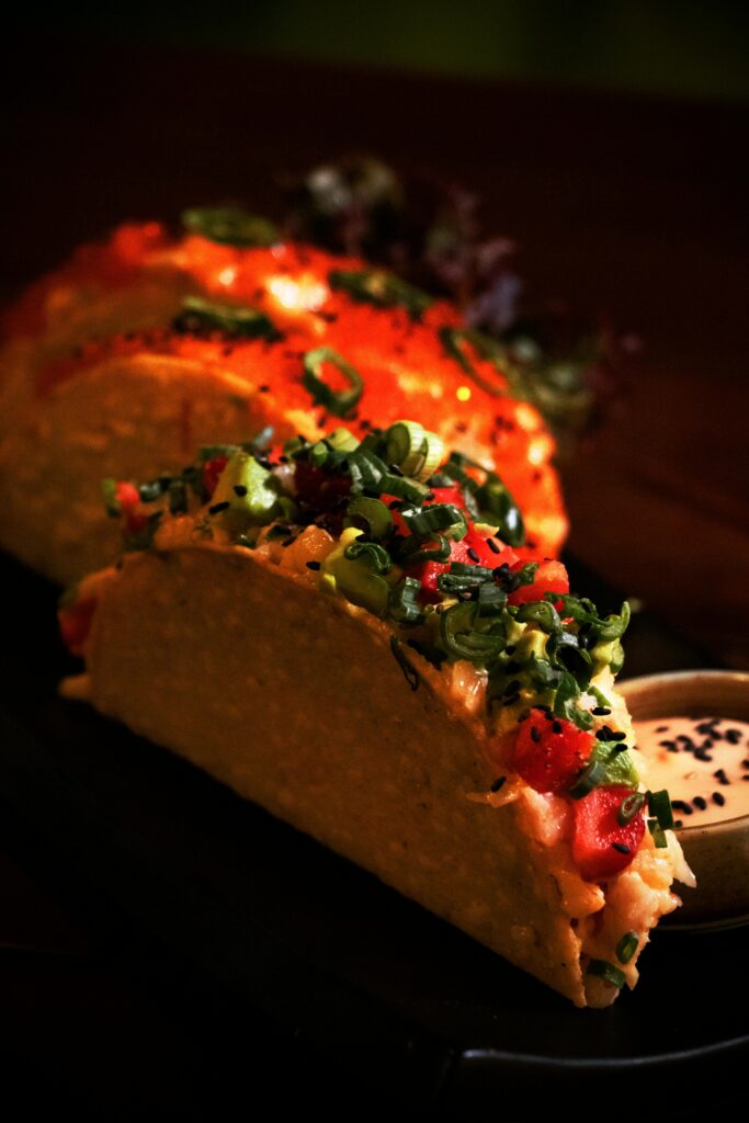 Savor the vibrant flavors of gourmet Birria Tacos topped with fresh ingredients and served with dipping sauce.