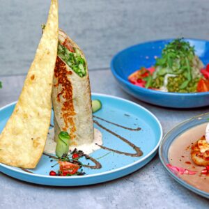 A vibrant display of gourmet brunch dishes on colorful plates, featuring wraps and fresh greens.