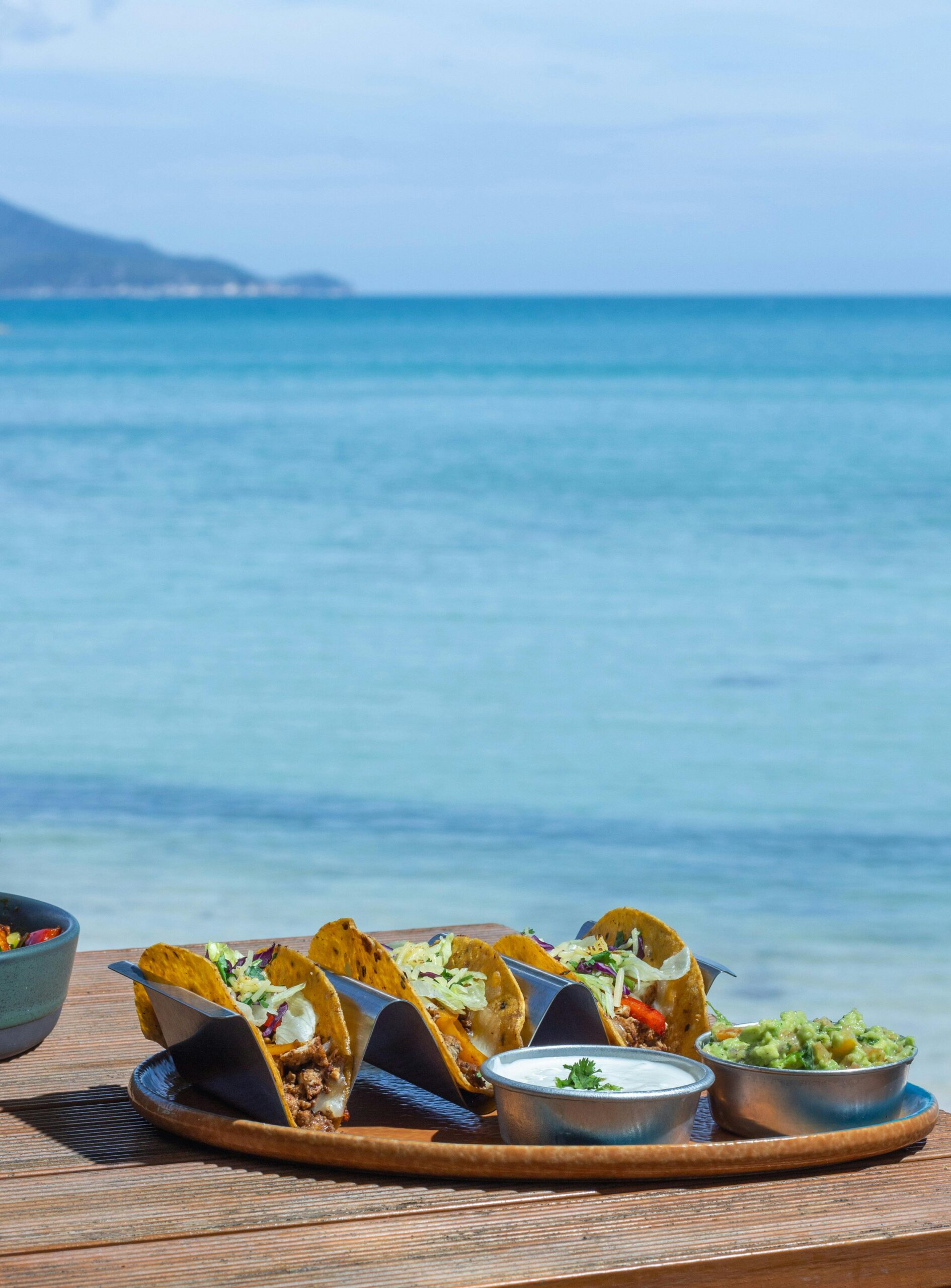 Delicious tacos with guacamole by the beach, offering a perfect tropical lunch vibe.