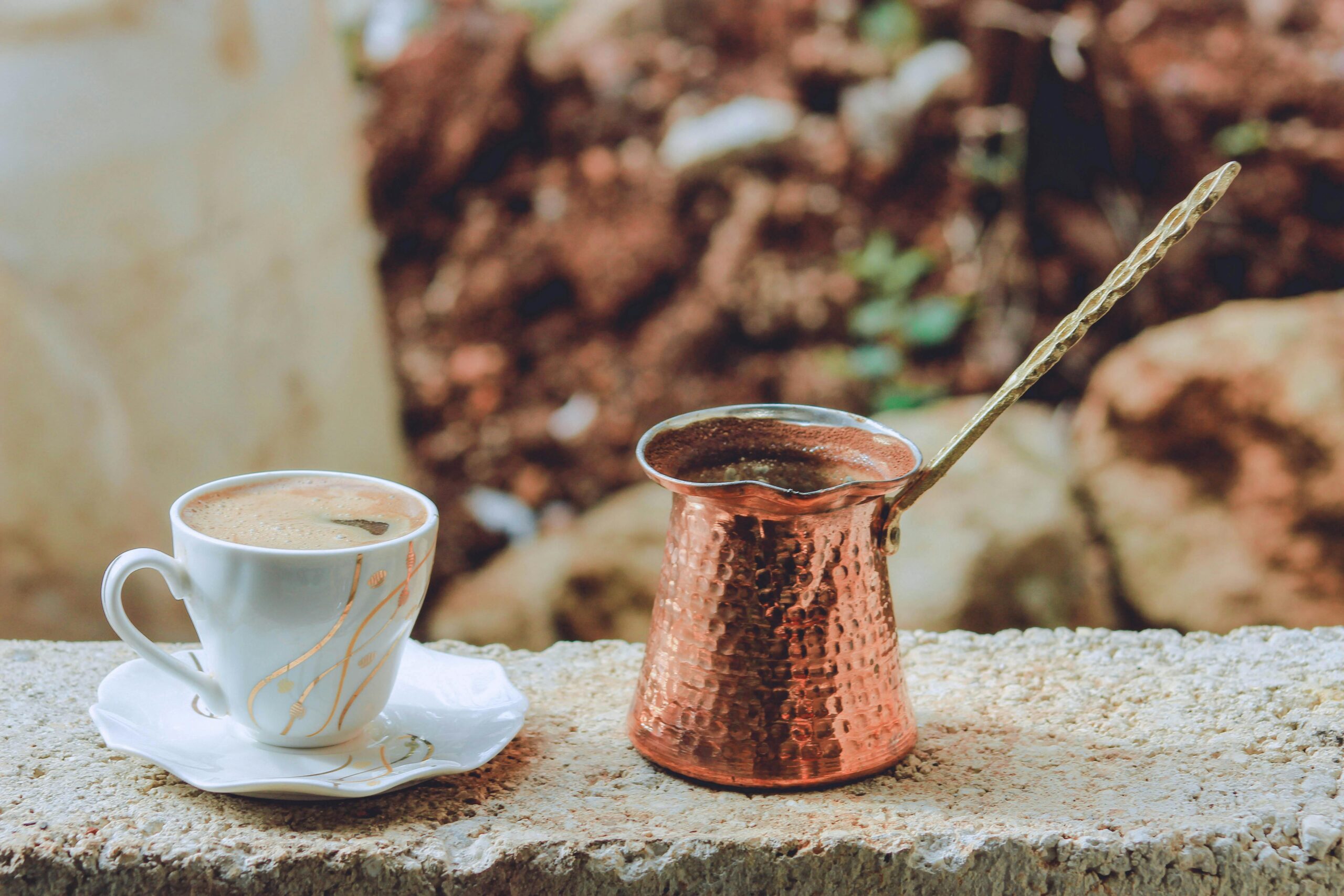 Discover the rich flavors of Turkish coffee served in a porcelain cup with a traditional copper cezve outdoors.