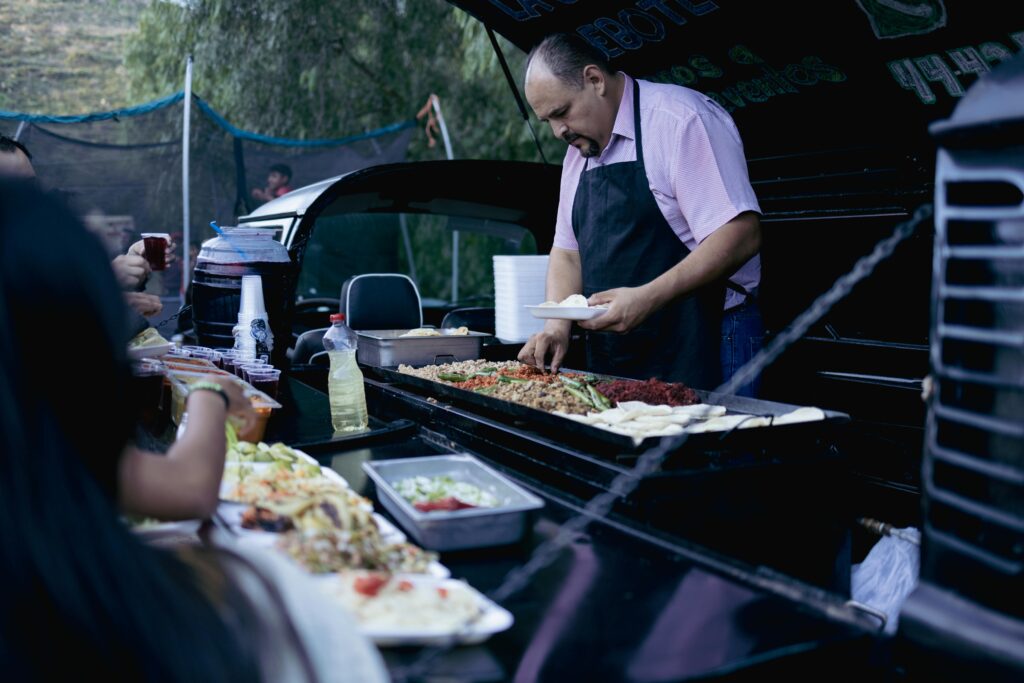 A street food vendor in San Luis Potosi prepares and serves tacos to customers at an outdoor market.
