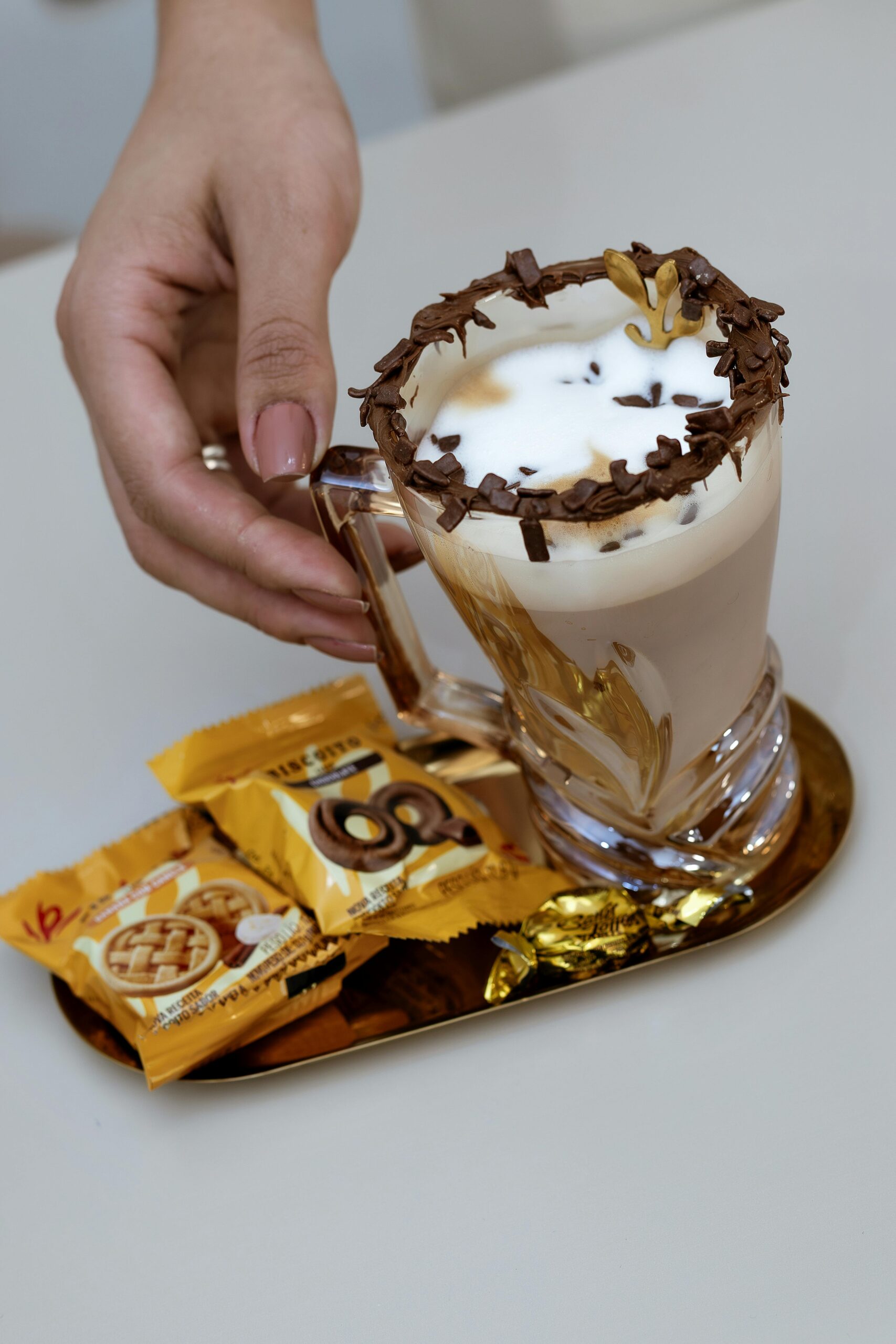 Luxury latte with chocolate shavings and biscuits on a gold tray. Perfect for gourmet presentations.