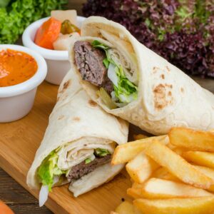 Savory shawarma wrap with crispy fries and dipping sauce, perfect for lunch or dinner.