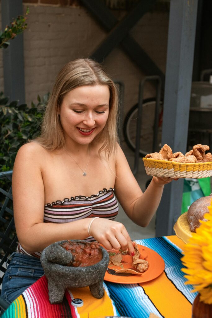 Woman enjoying tacos with salsa in a vibrant outdoor setting, capturing a moment of joy and flavor.